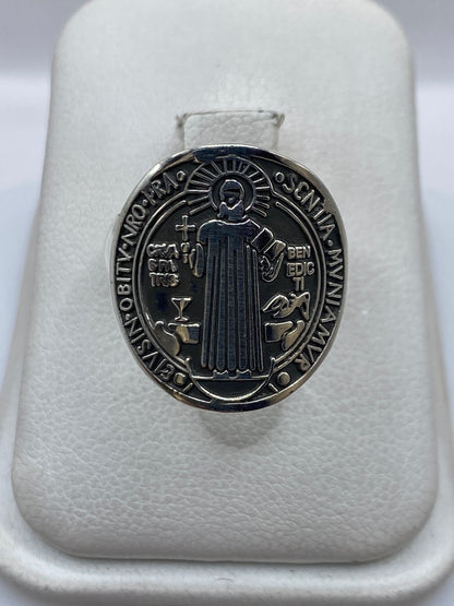 Anillo de plata con medallón Saint Benedict, visto de frente sobre soporte blanco