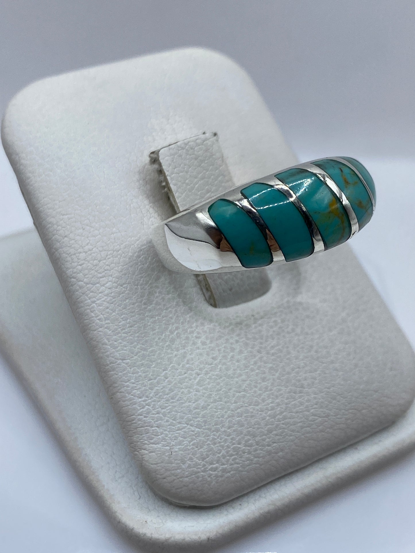 Detalle lateral del anillo unisex mostrando el engaste individual de cada turquesa en plata