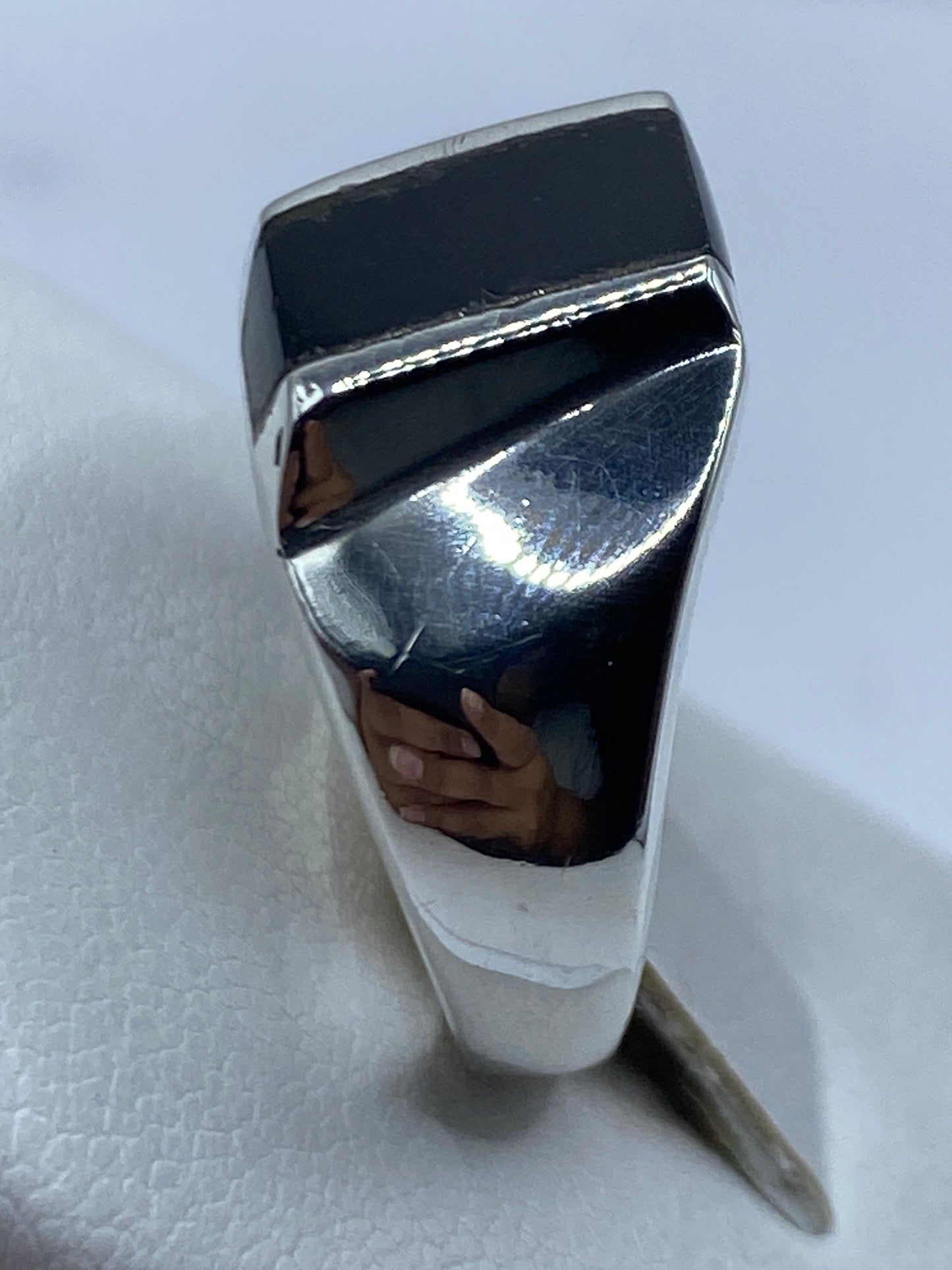 Anillo en mano, tono negro profundo, diseño geométrico limpio