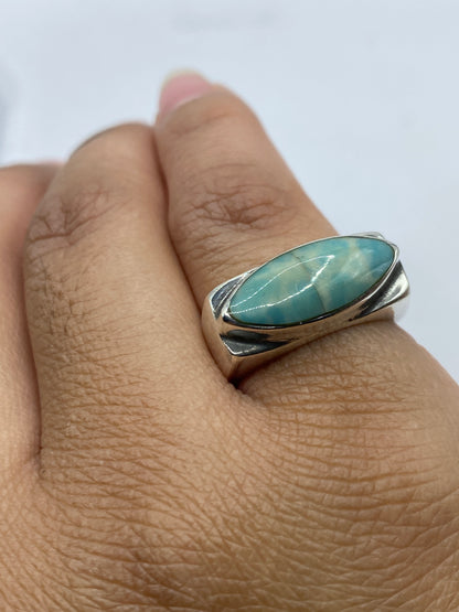 Anillo puesto en dedo, piedra azul cielo brillando contra la piel
