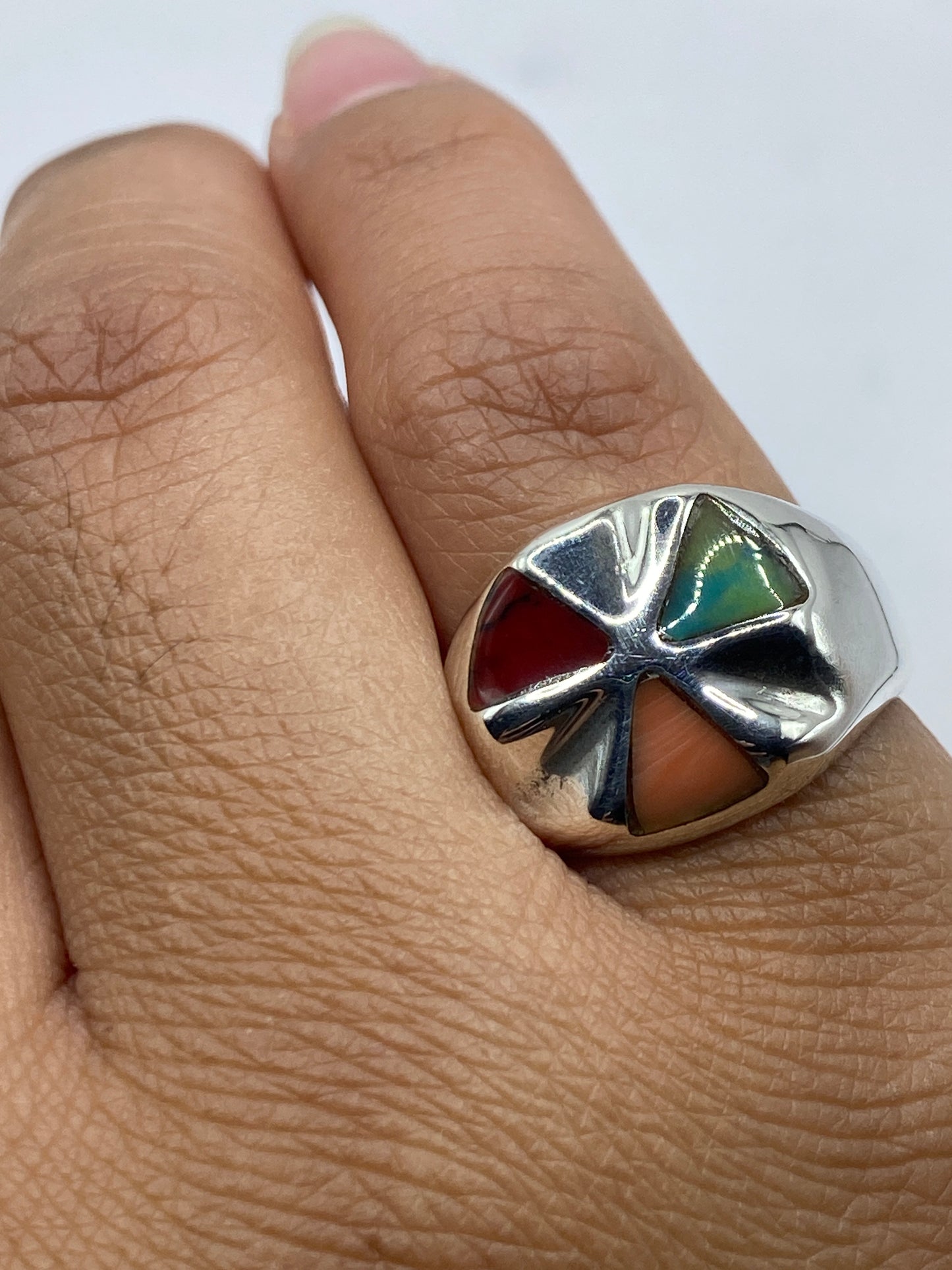Anillo en la mano mostrando el brillo del coral rojo y el pulido de la plata