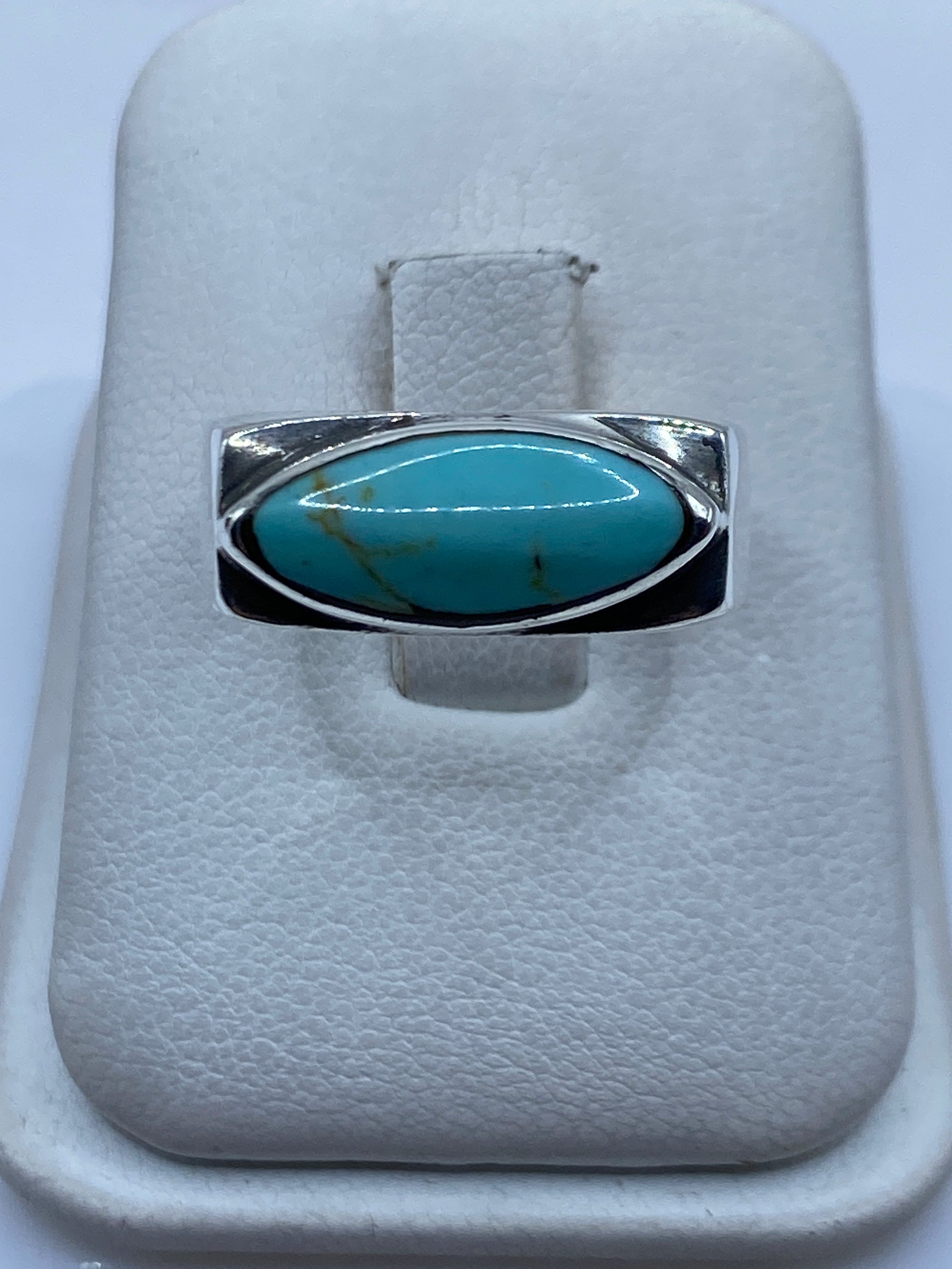 Anillo de plata .925 con turquesa azul cielo engastada, visto de frente sobre almohadilla blanca