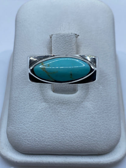Anillo de plata .925 con turquesa azul cielo engastada, visto de frente sobre almohadilla blanca