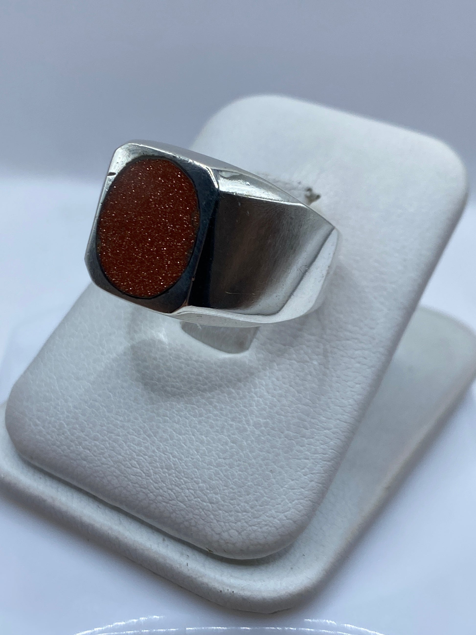 Detalle lateral del anillo unisex mostrando el engaste de la piedra y la plata pulida