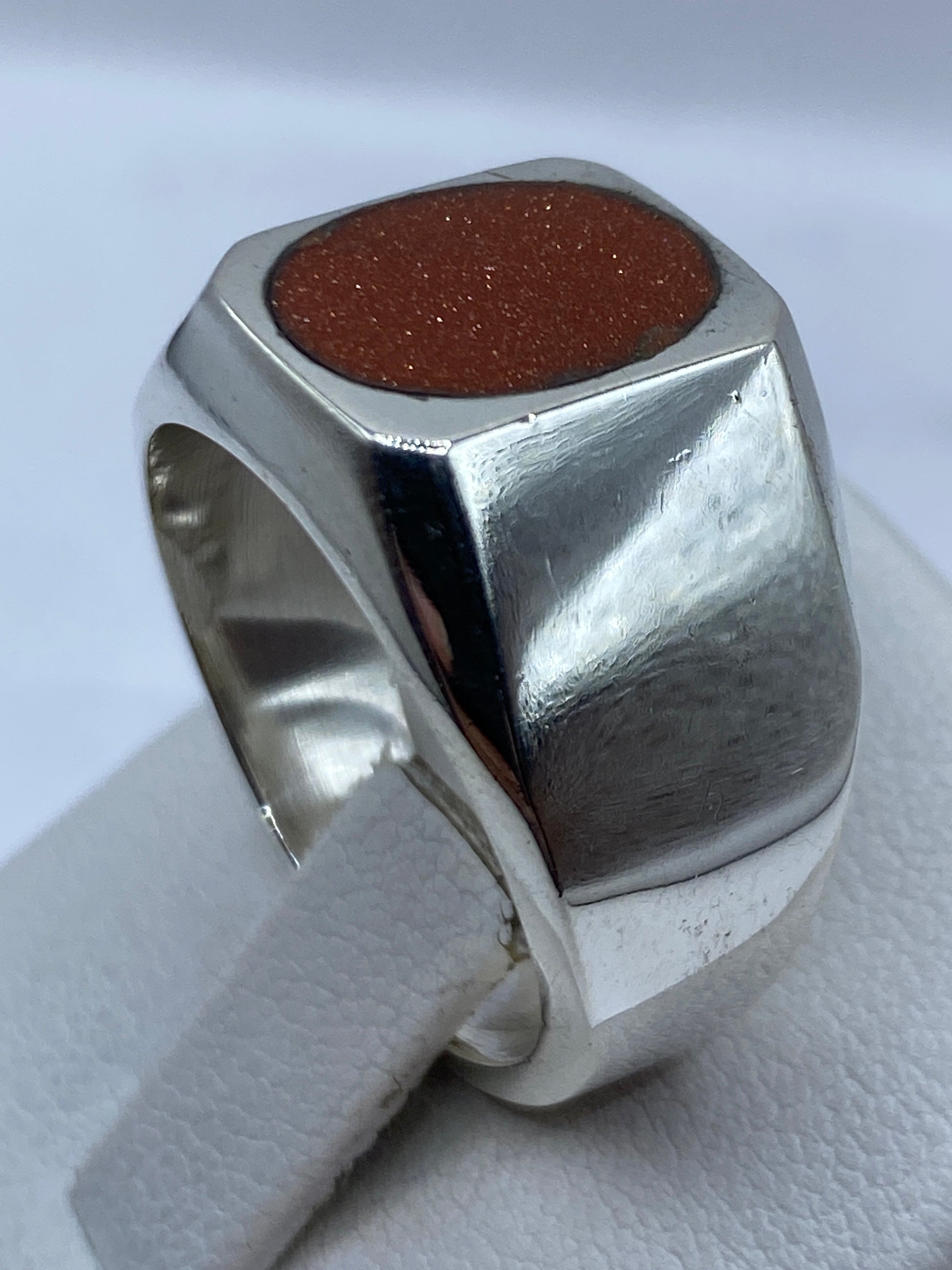 Anillo en dedo de la mano mostrando el tono café de la piedra contra la piel