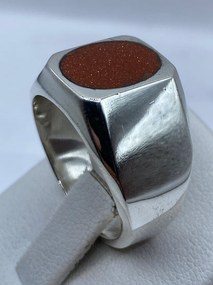 Anillo en dedo de la mano mostrando el tono café de la piedra contra la piel