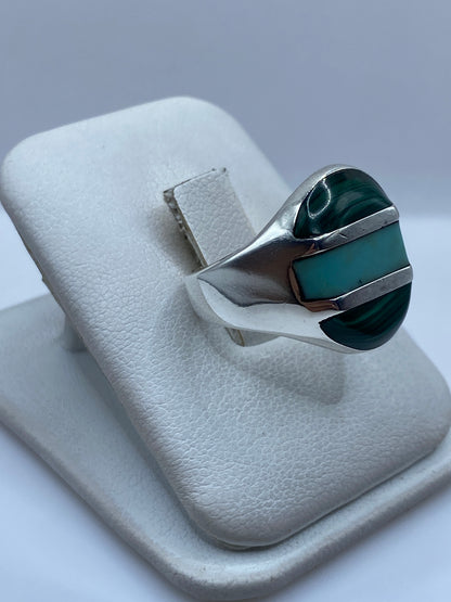 Anillo de plata y malaquita puesto en el dedo, mostrando el verde natural de la piedra