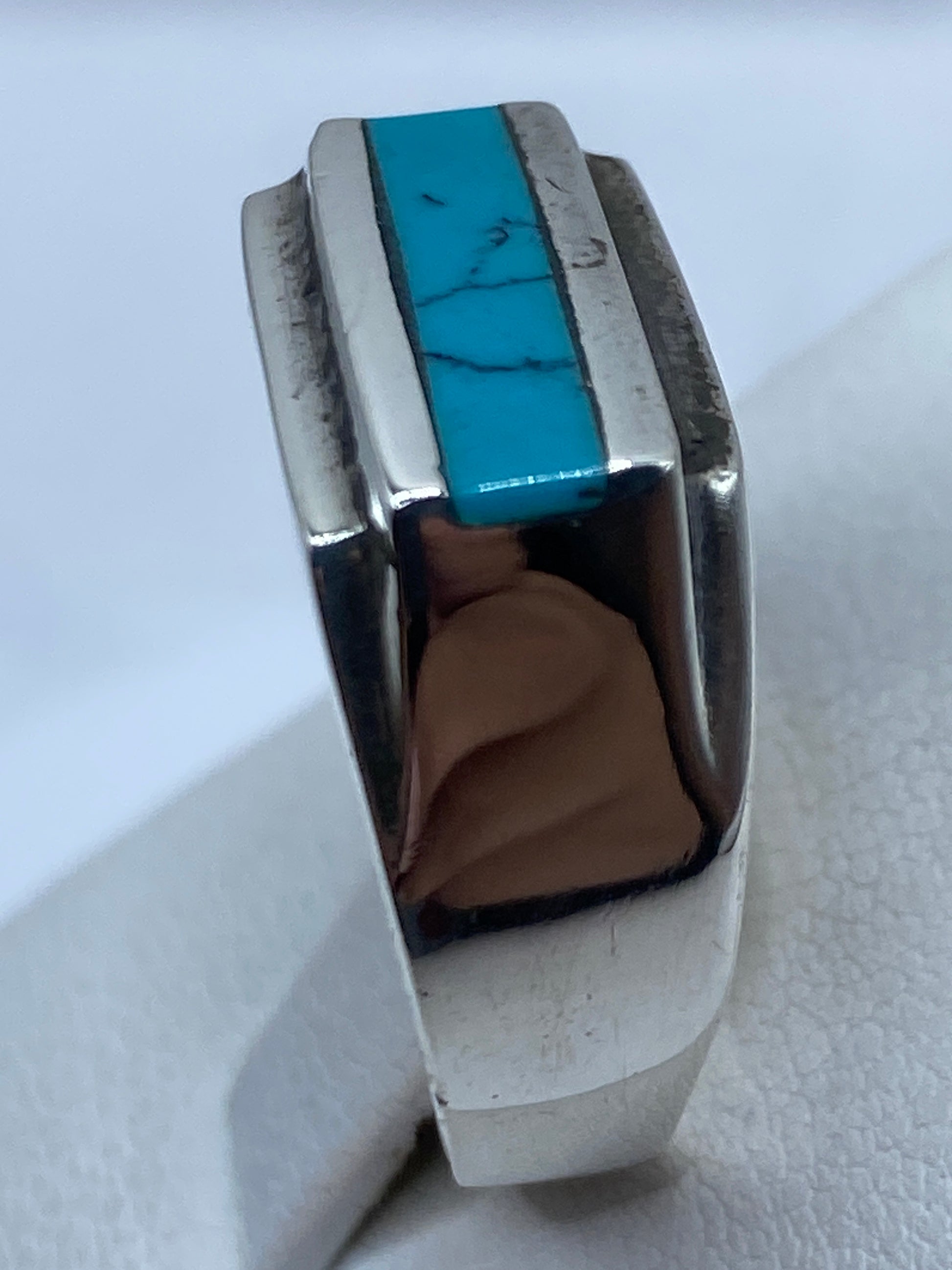 Anillo con turquesa en la mano, mostrando el tono azul cielo y el brillo de la plata