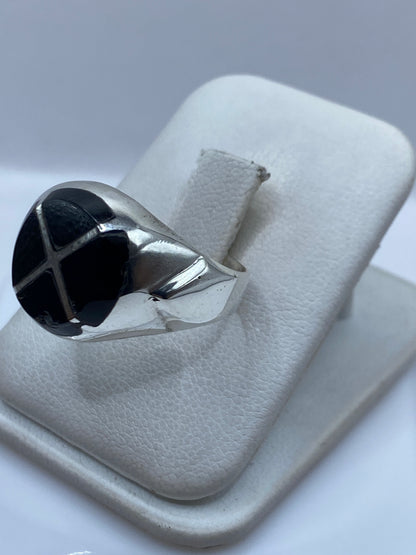 Anillo de plata con ónix negro en la mano, mostrando el engaste y el brillo del metal