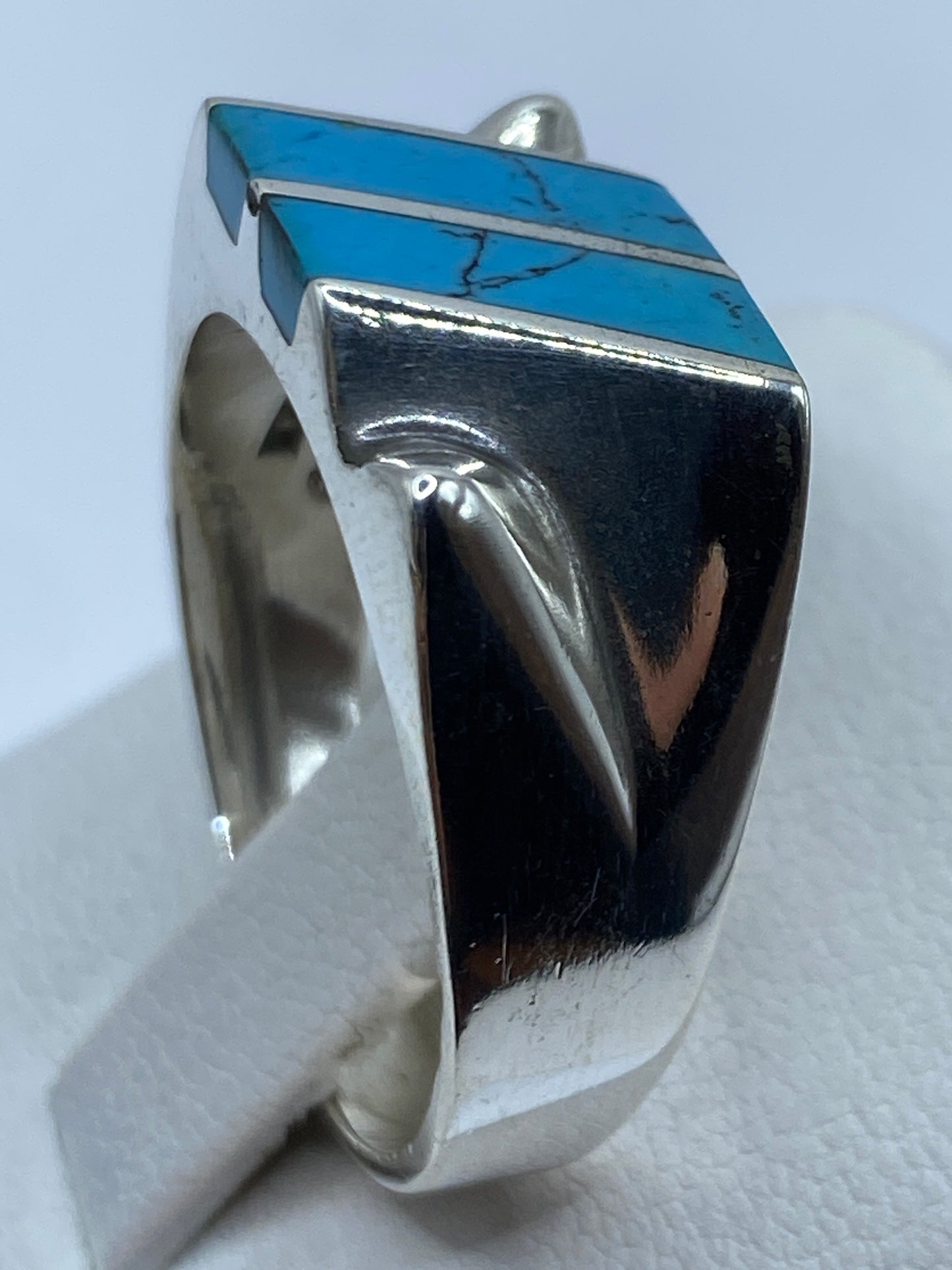 Detalle lateral del anillo de plata con incrustación de turquesa y hombros tallados