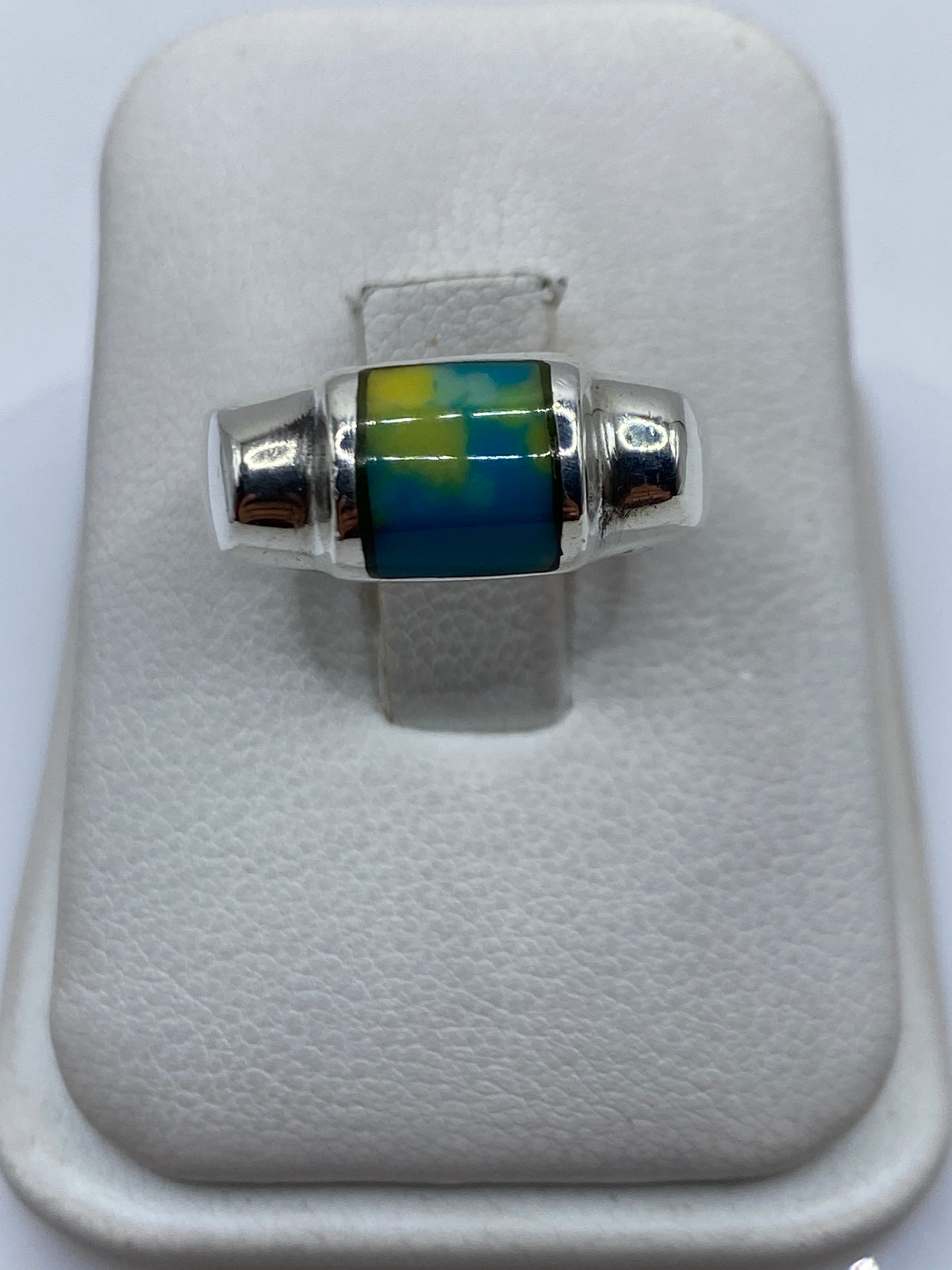Anillo de plata con piedra azul incrustada, vista frontal en estuche blanco