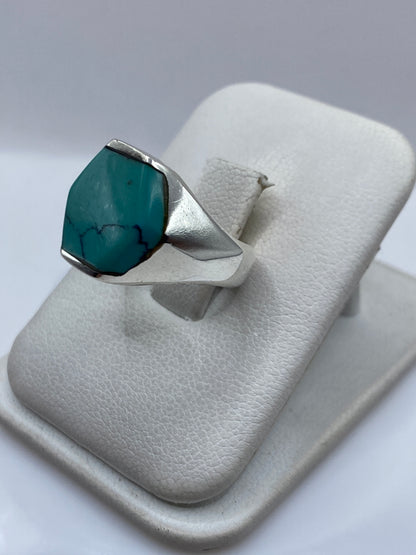 Anillo de plata con turquesa en la mano, tono azul verdoso natural