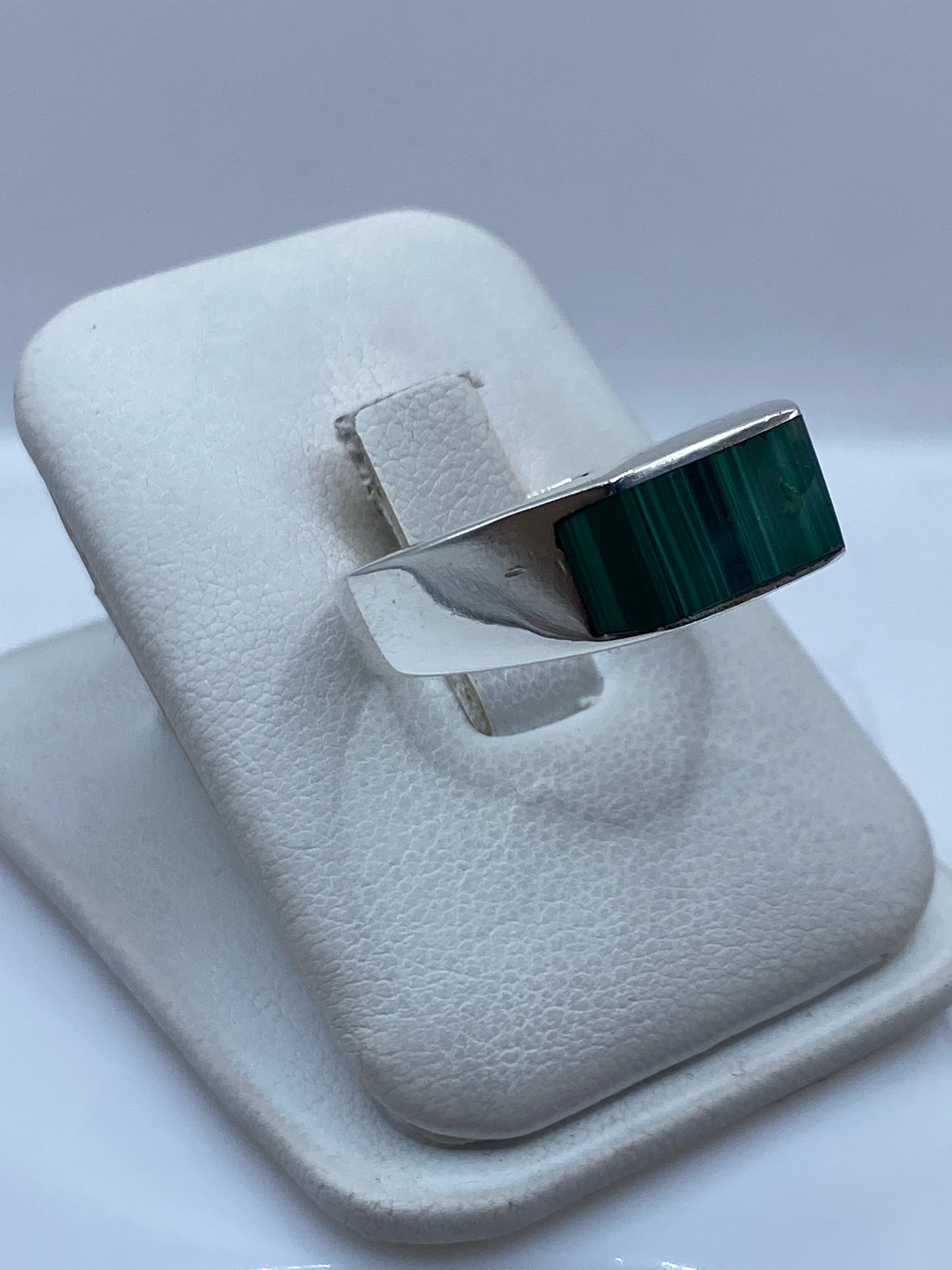Anillo de plata malaquita verde en dedo de hombre, mostrando el peso y presencia