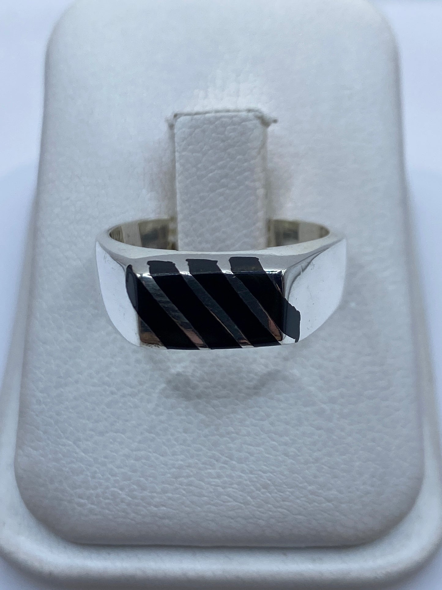 Anillo de plata con ónix negro engastado en la mano de una persona