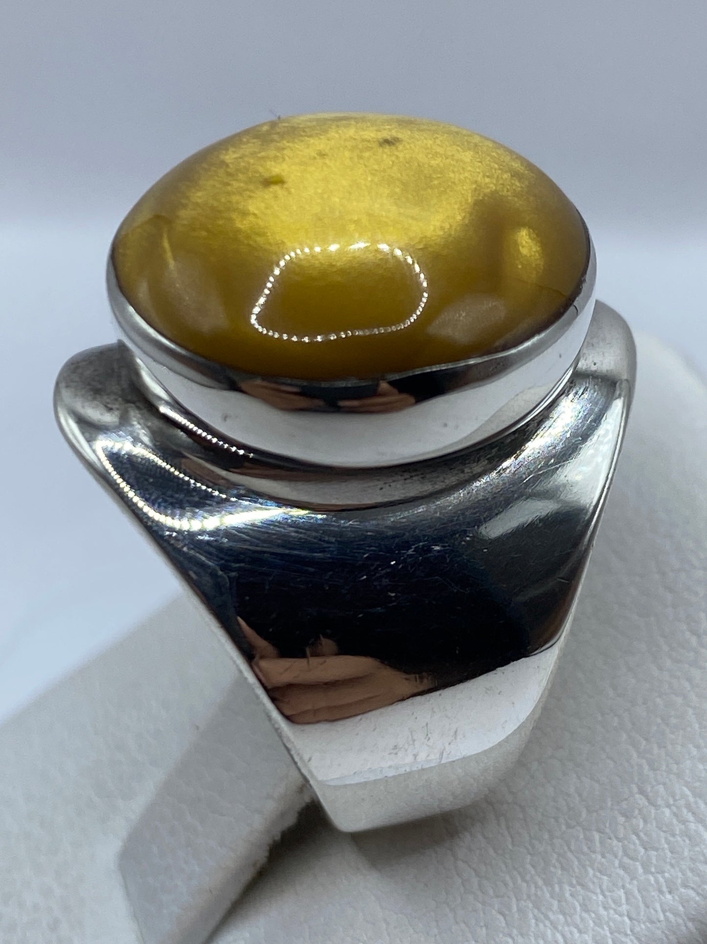 Anillo en mano de mujer, luz reflejada en la plata y piedra café