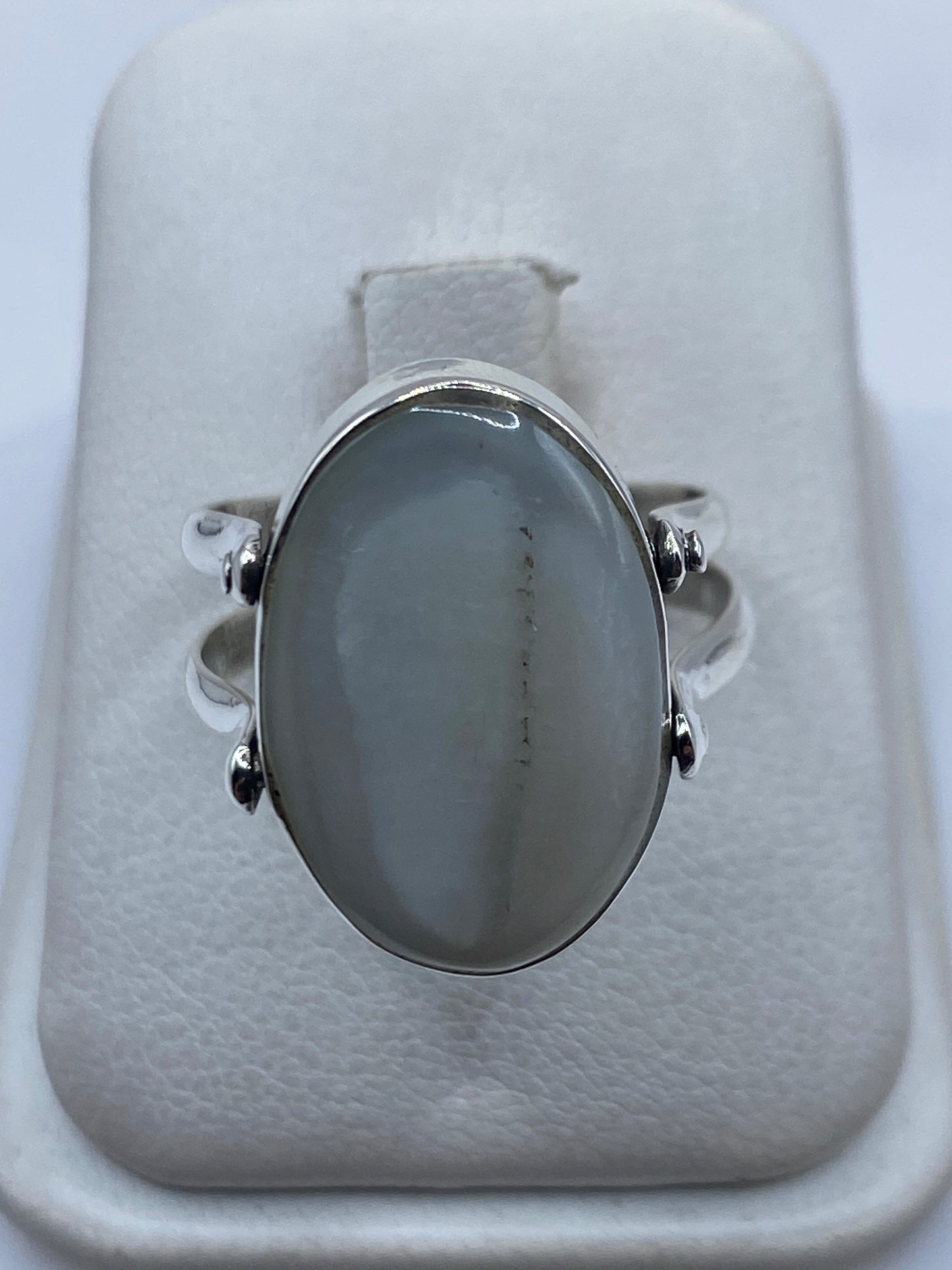 Anillo de plata con perla blanca engastada en la mano de una mujer