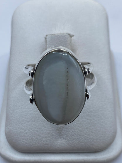 Anillo de plata con perla blanca engastada en la mano de una mujer