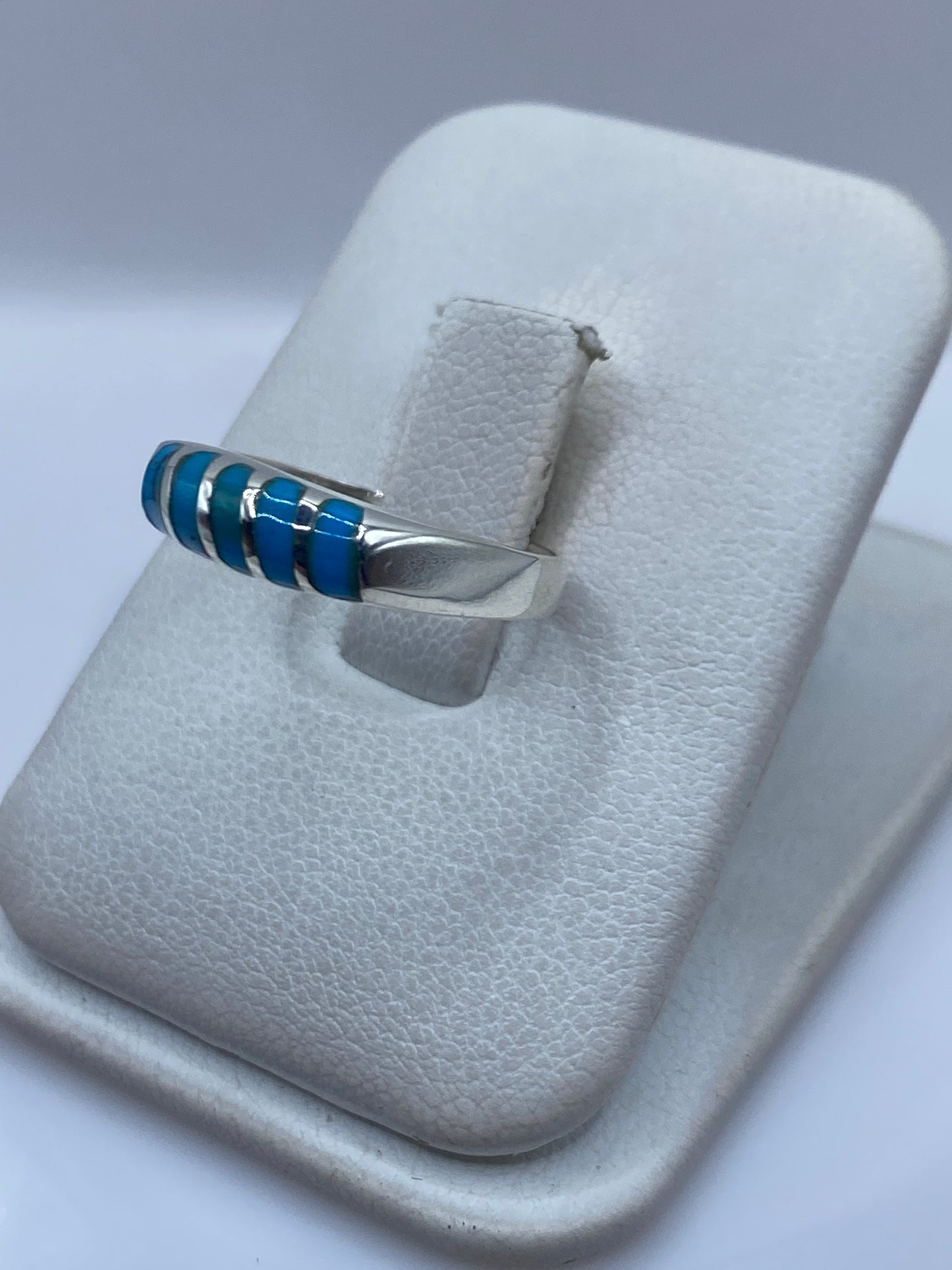 Detalle del anillo mostrando el engaste a mano de la turquesa entre franjas de plata