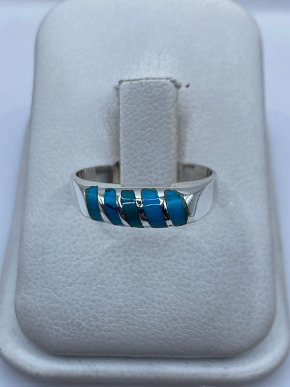 Anillo de plata con cinco incrustaciones de turquesa azul cielo en la mano