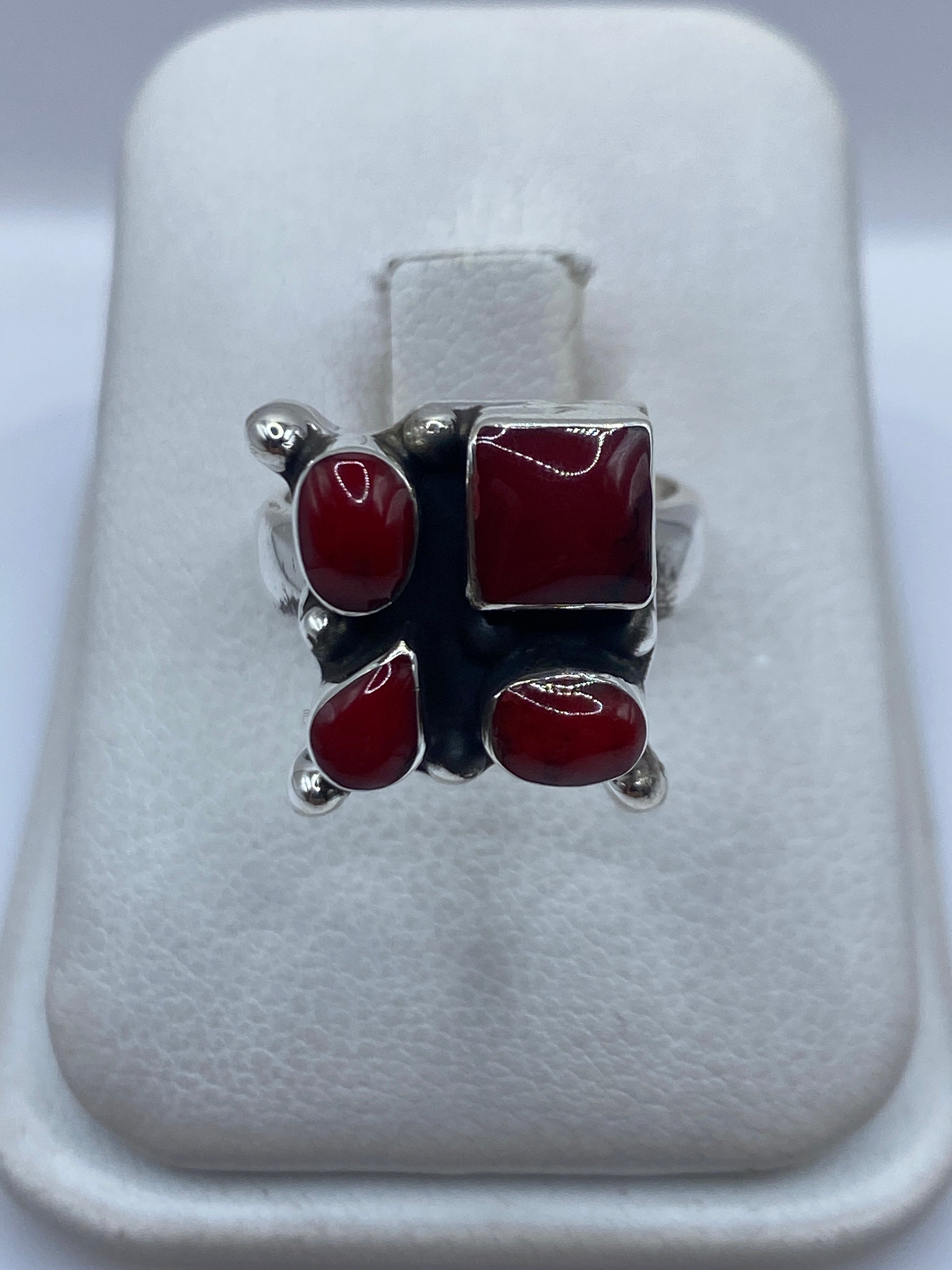 Anillo de plata .925 con cuatro cabujones de coral rojo engastado, diseño geométrico en mano de mujer
