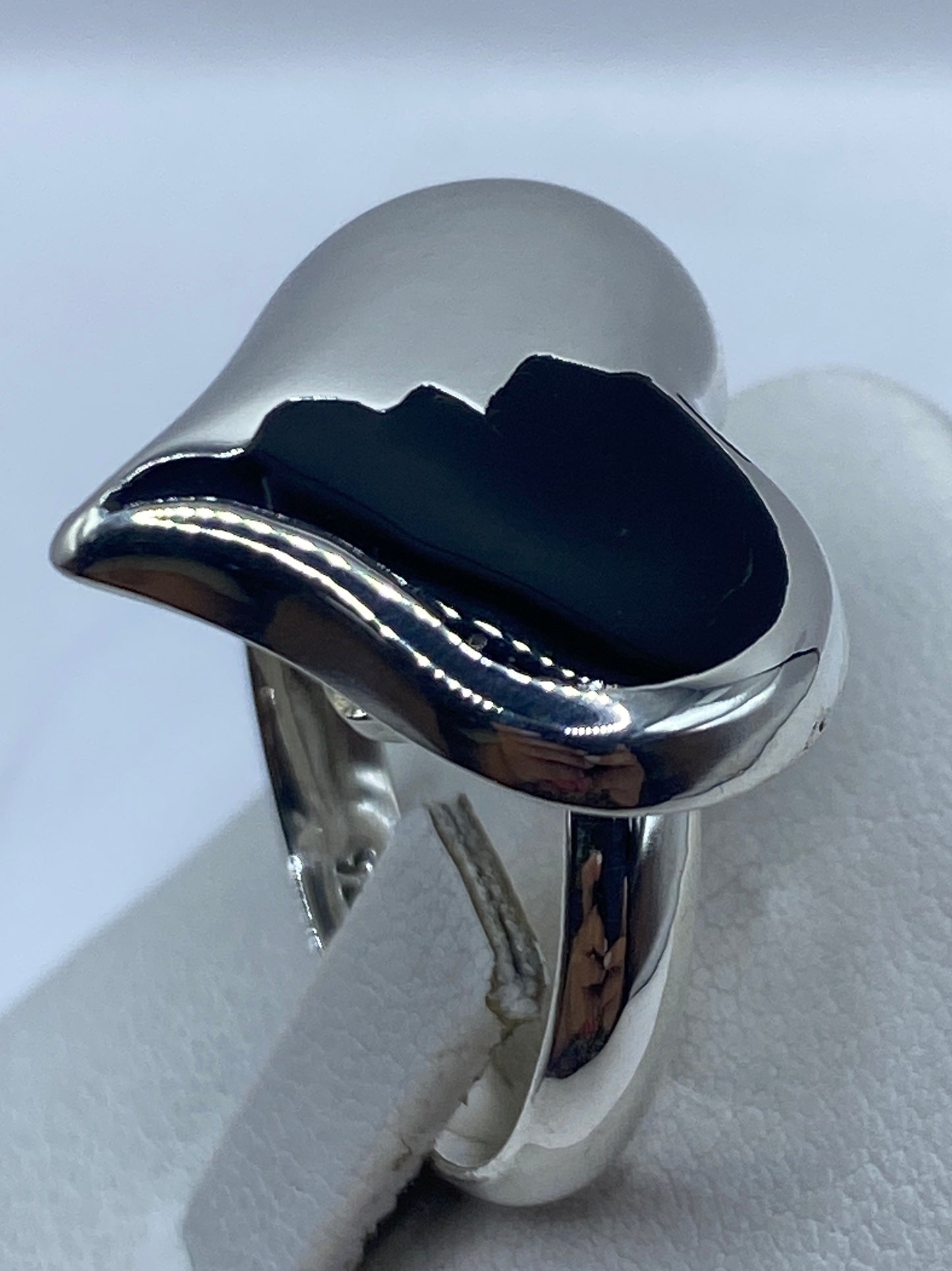 Anillo ajustable de ónix negro puesto en la mano de una mujer, mostrando el pulido espejo de la plata