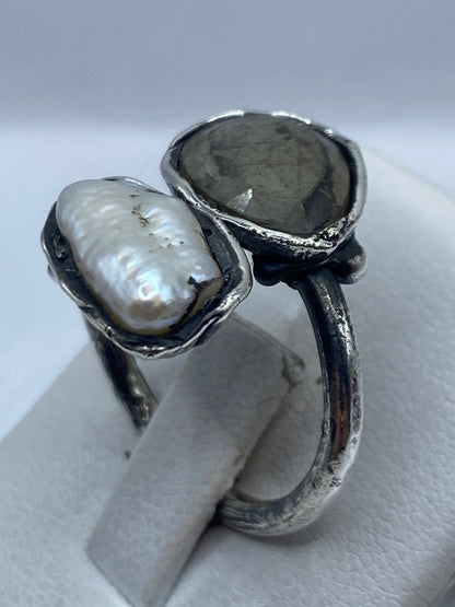 Anillo de plata con perla en la mano de una mujer, mostrando el engaste artesanal