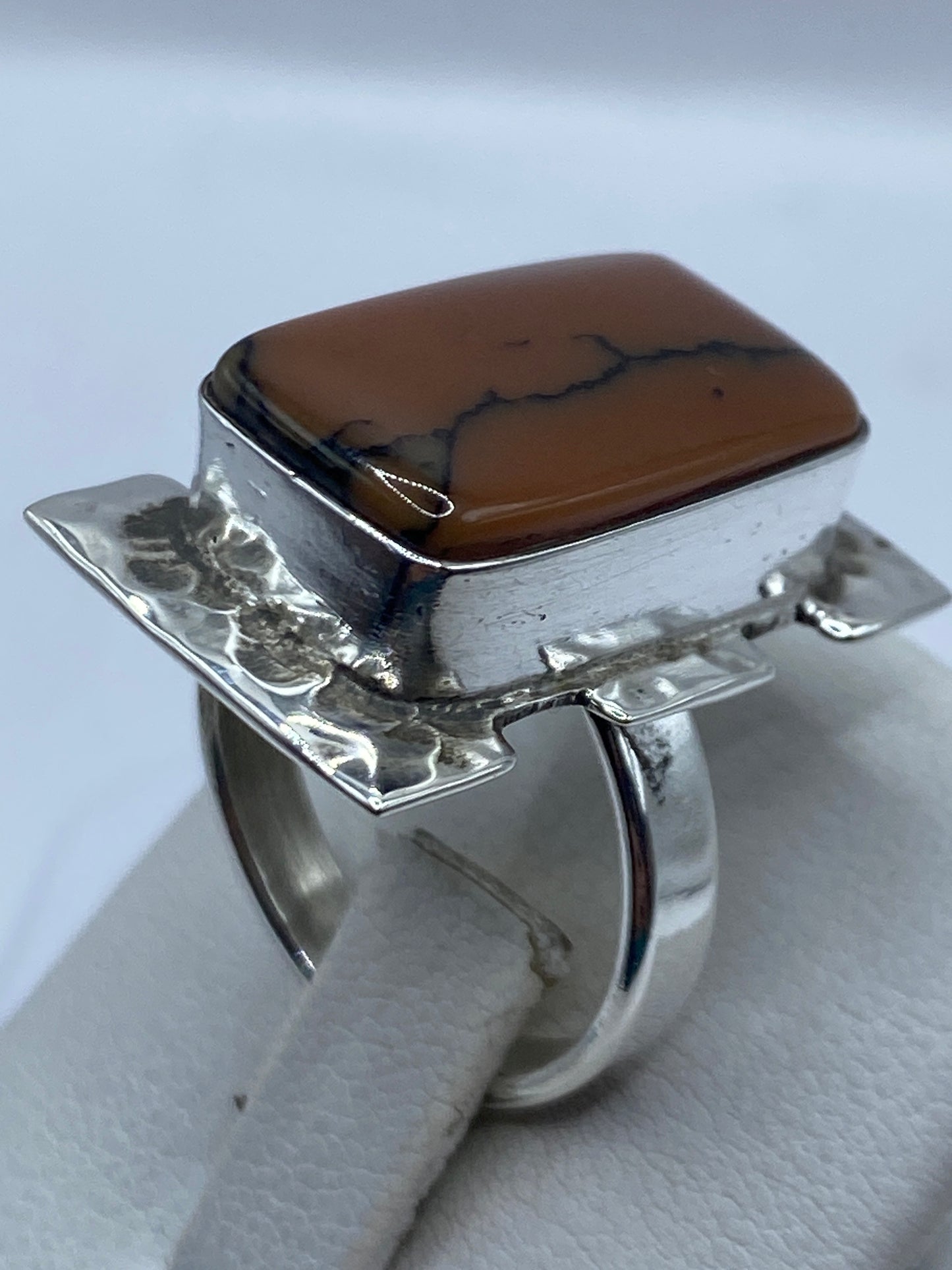 Detalle del engaste a mano y la piedra café en anillo de plata pulida