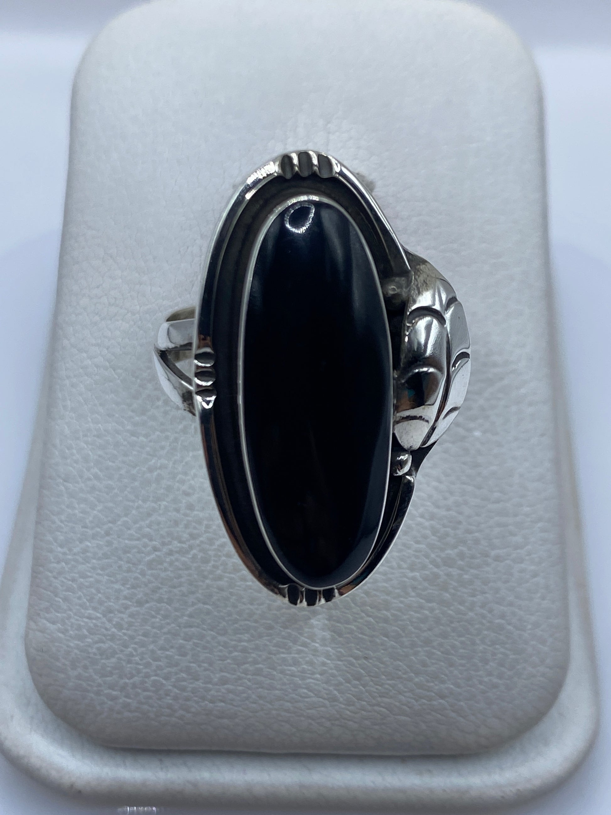 Anillo de plata con ónix negro y manos escultóricas a los lados, vista frontal