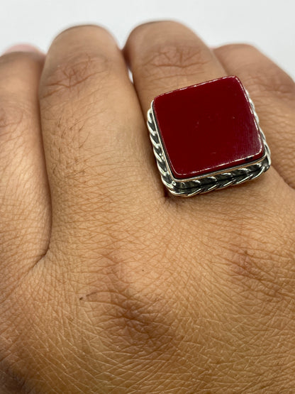 Anillo de plata con coral puesto en dedo, mostrando el color rojo cálido