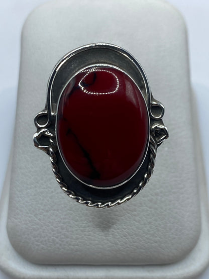 Anillo de plata ajustable con coral rojo vivo en mano de mujer