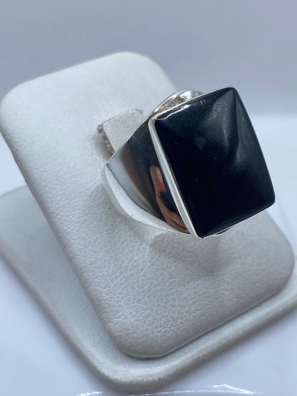 Anillo de plata con ónix negro en la mano, mostrando el contraste entre la piedra y la plata pulida