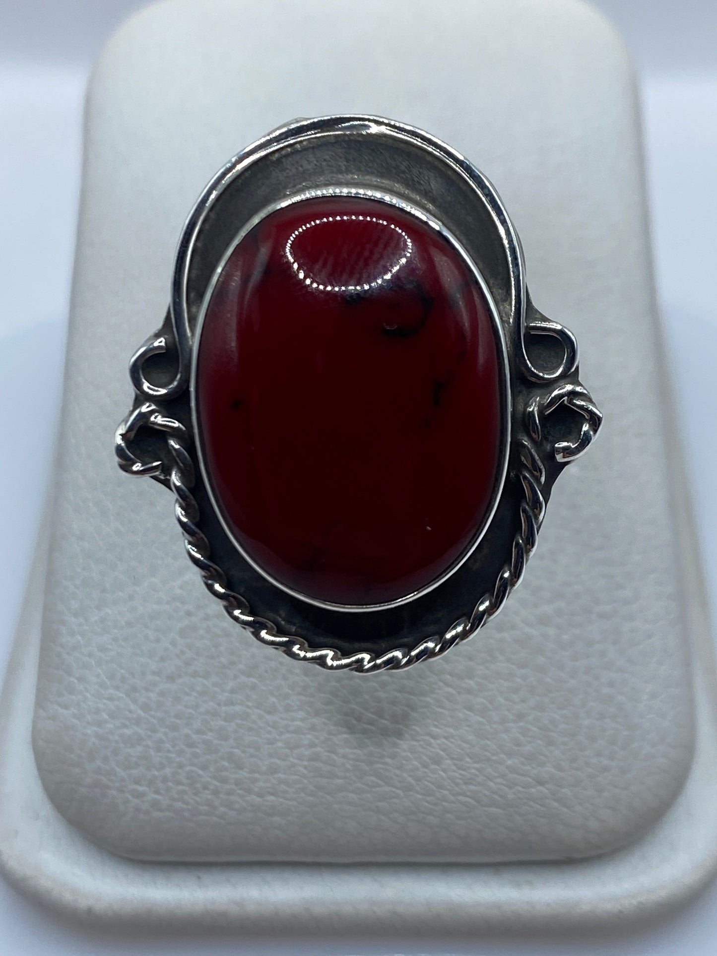 Anillo de plata ajustable con coral rojo engastado en la mano de una mujer