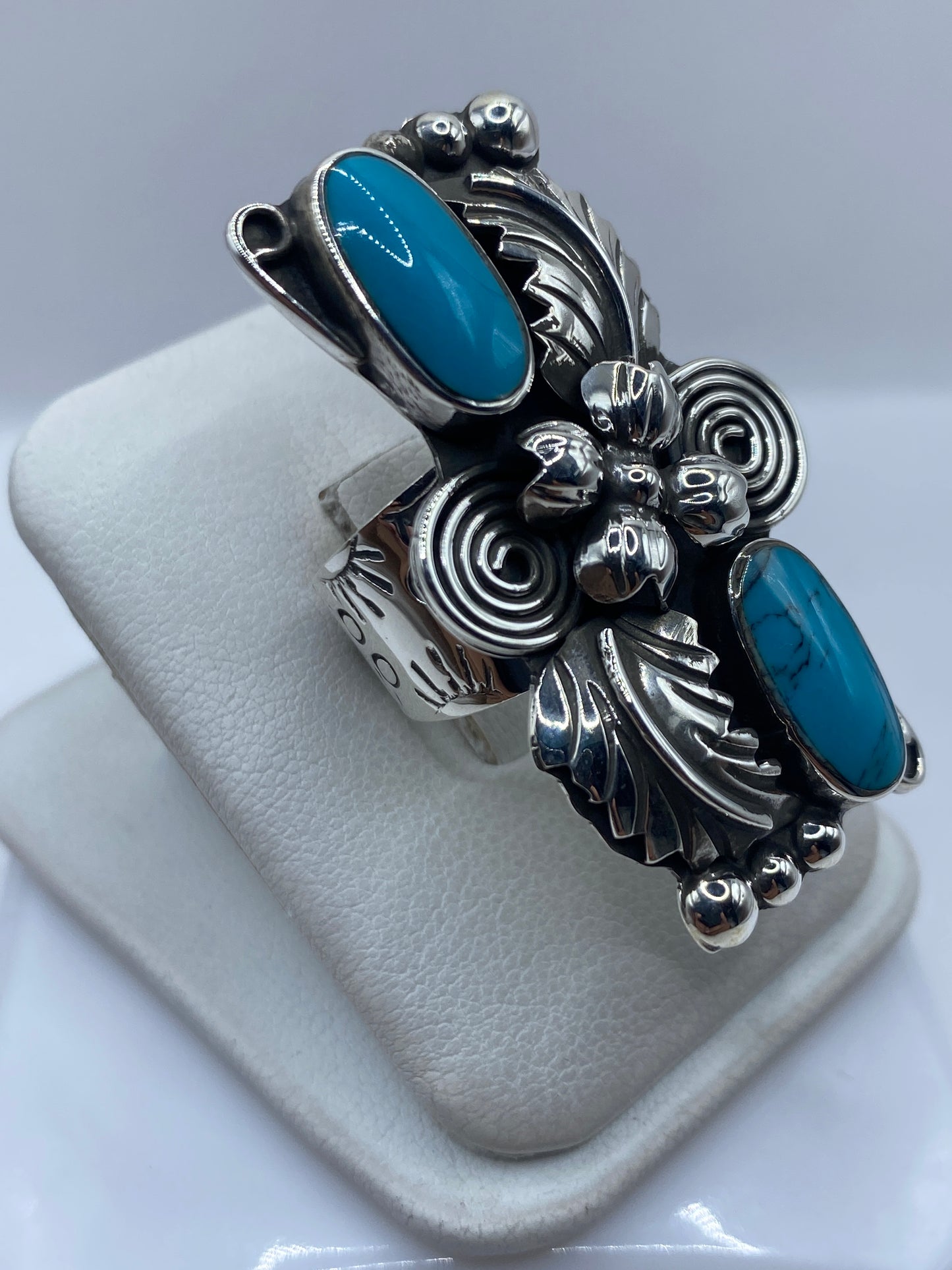 Detalle lateral del anillo mostrando el engaste de turquesa a mano y la textura repujada de la plata