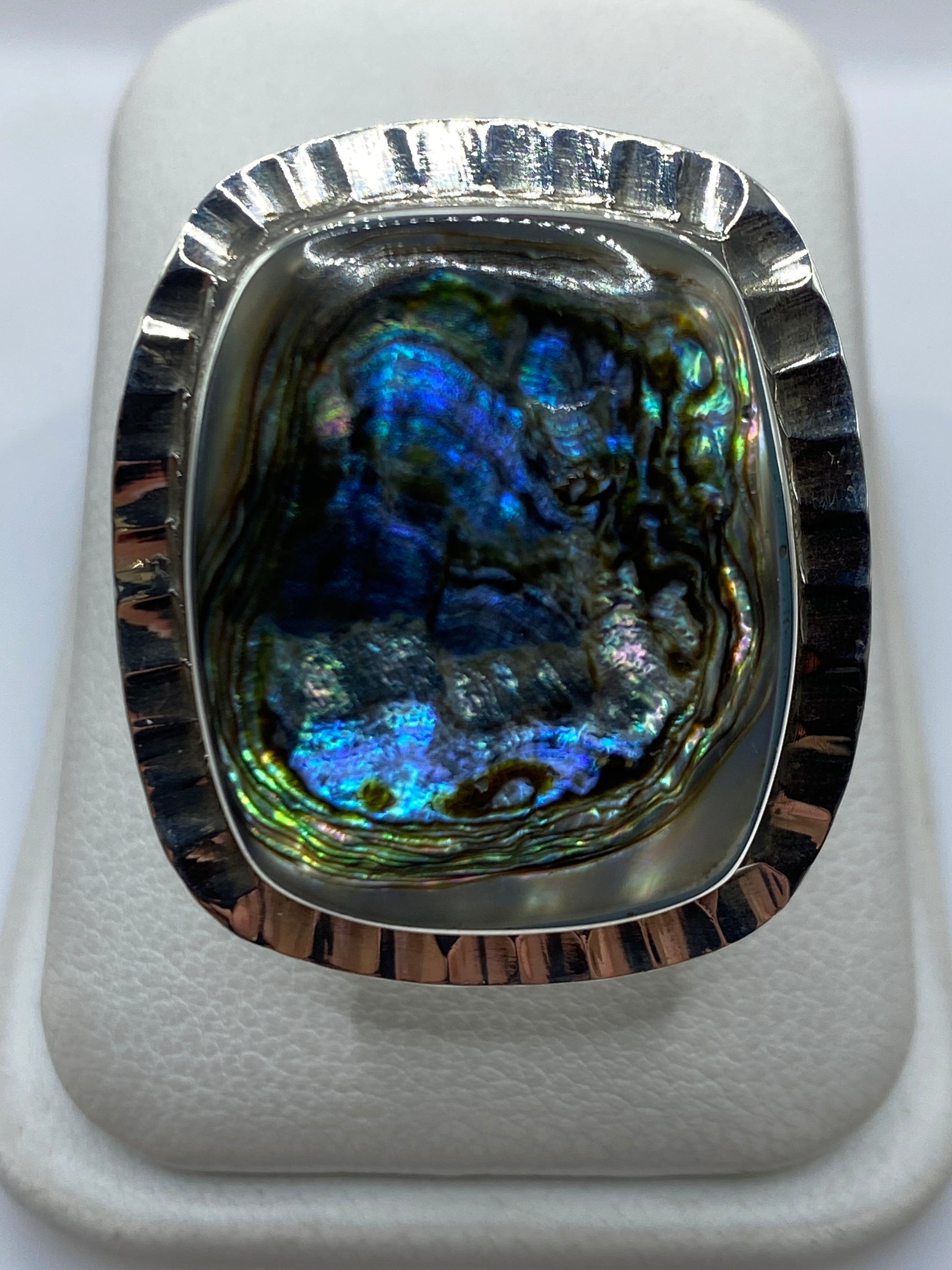 Anillo de plata ajustable con piedra iridiscente azul y verde en la mano