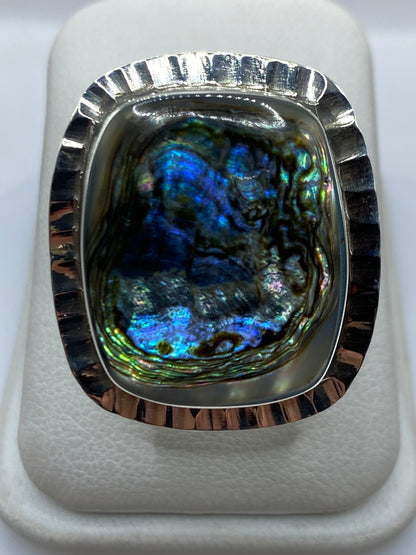 Anillo de plata ajustable con piedra iridiscente azul y verde en la mano