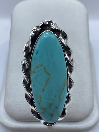 Anillo de plata con turquesa azul cielo en forma ovalada con cuerpo ondulado, sobre fondo blanco