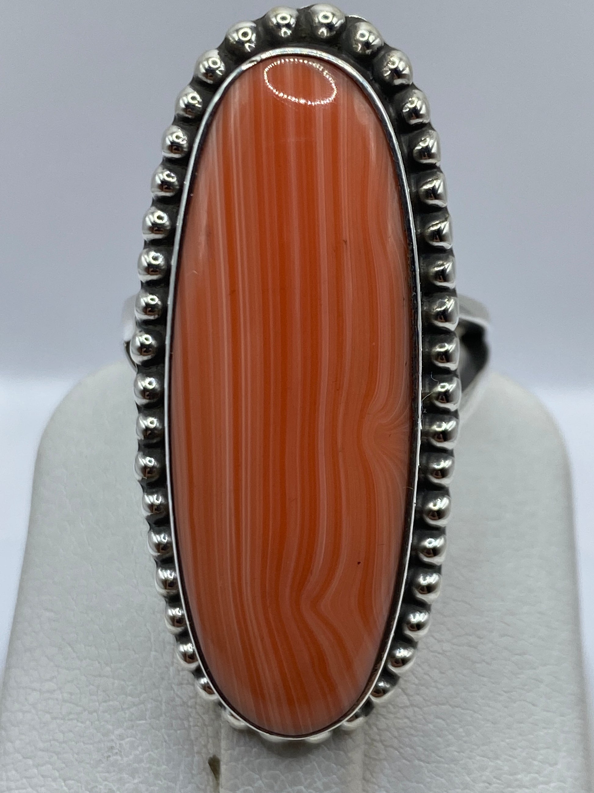 Anillo de coral engastado a mano en dedo de mujer, tonos cálidos