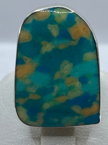 Anillo puesto en mano femenina destacando los tonos multicolor de la gema