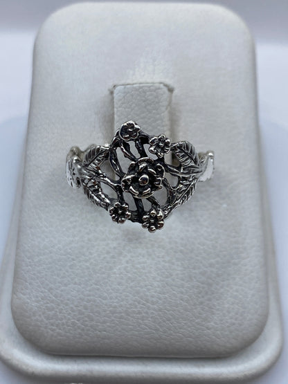Anillo de plata en calado con flores tridimensionales sobre estuche blanco