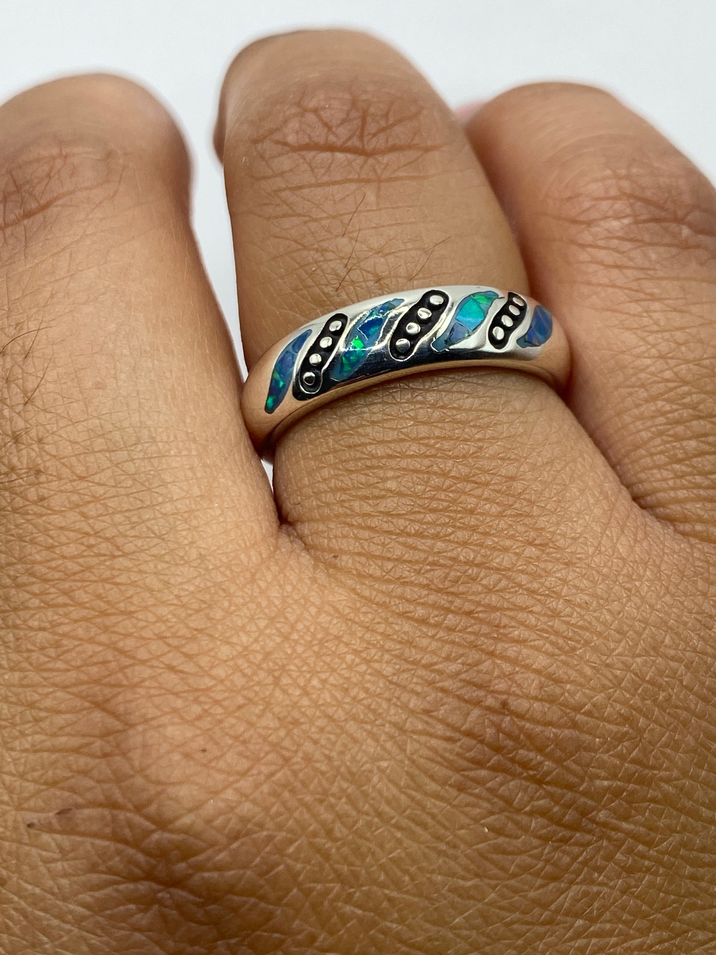 Anillo con ópalo azul en la mano, luz natural iluminando la piedra