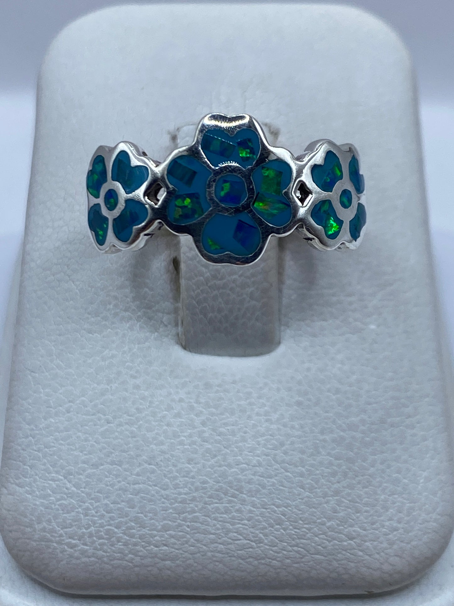 Anillo de plata con flores y ópalo de fuego azul cielo, vista frontal en estuche blanco