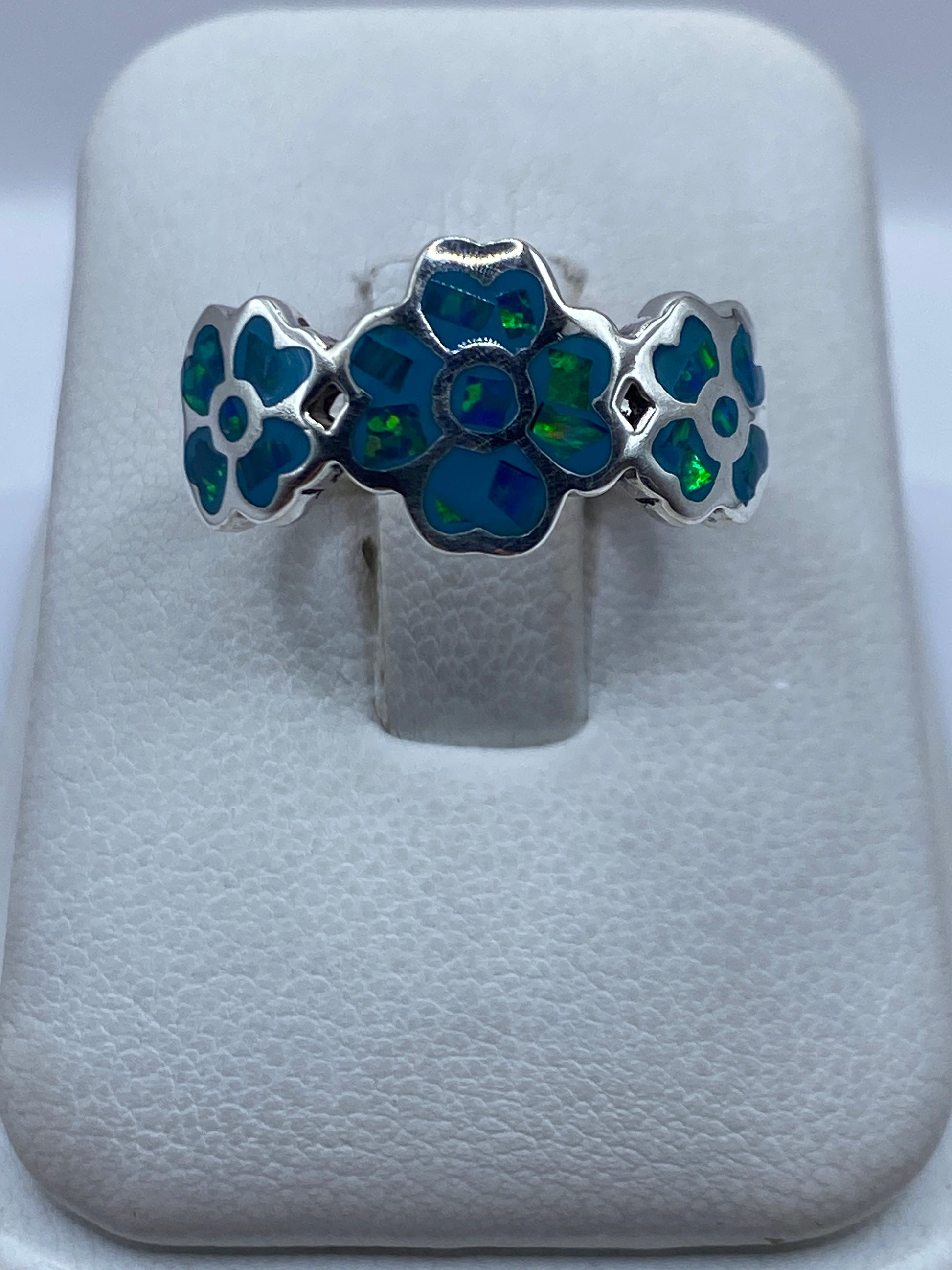 Anillo de plata con flores y ópalo de fuego azul cielo, vista frontal en estuche blanco