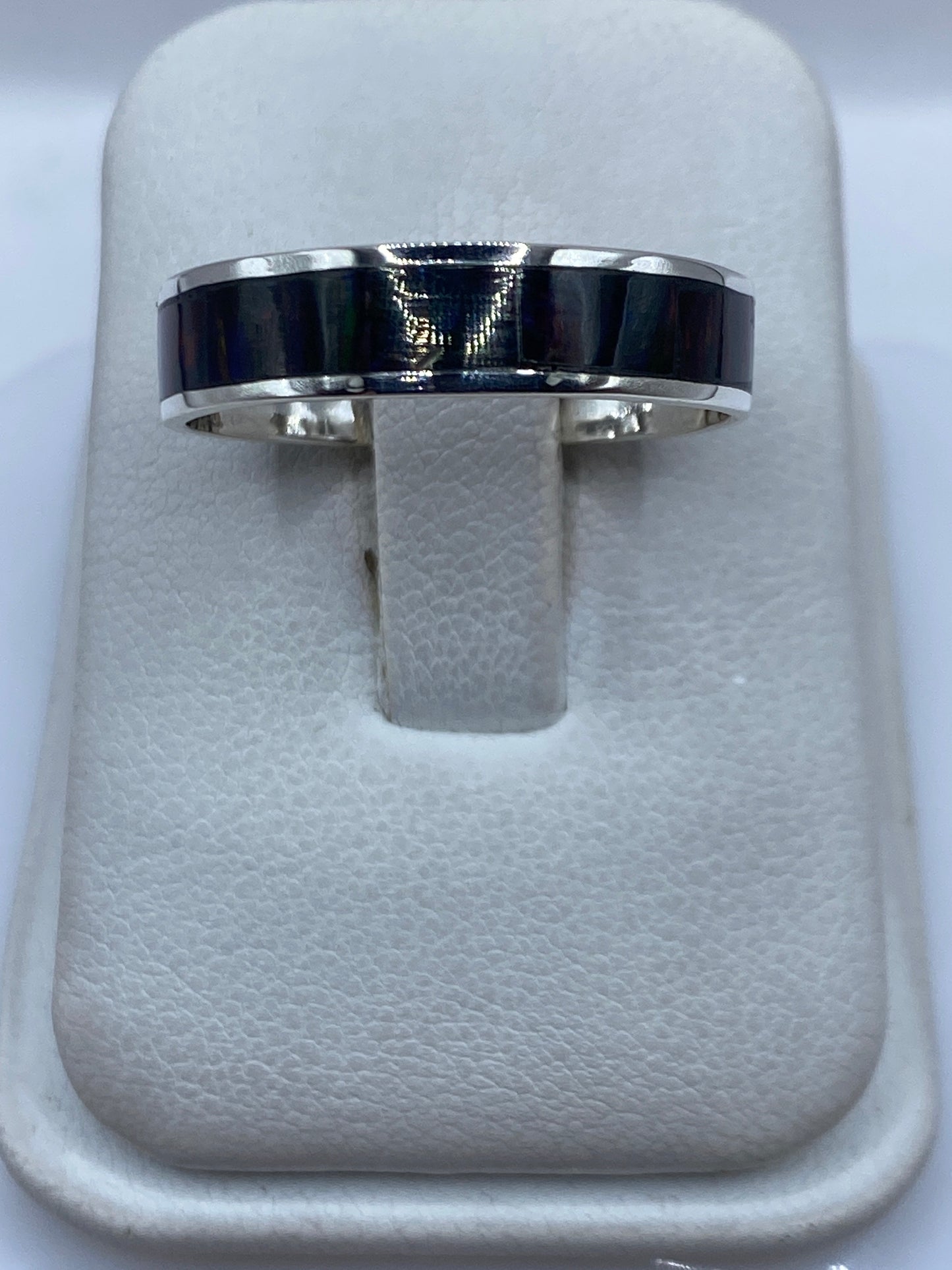 Anillo de plata .950 con ópalo de fuego multicolor en dedos de una mano sobre fondo blanco