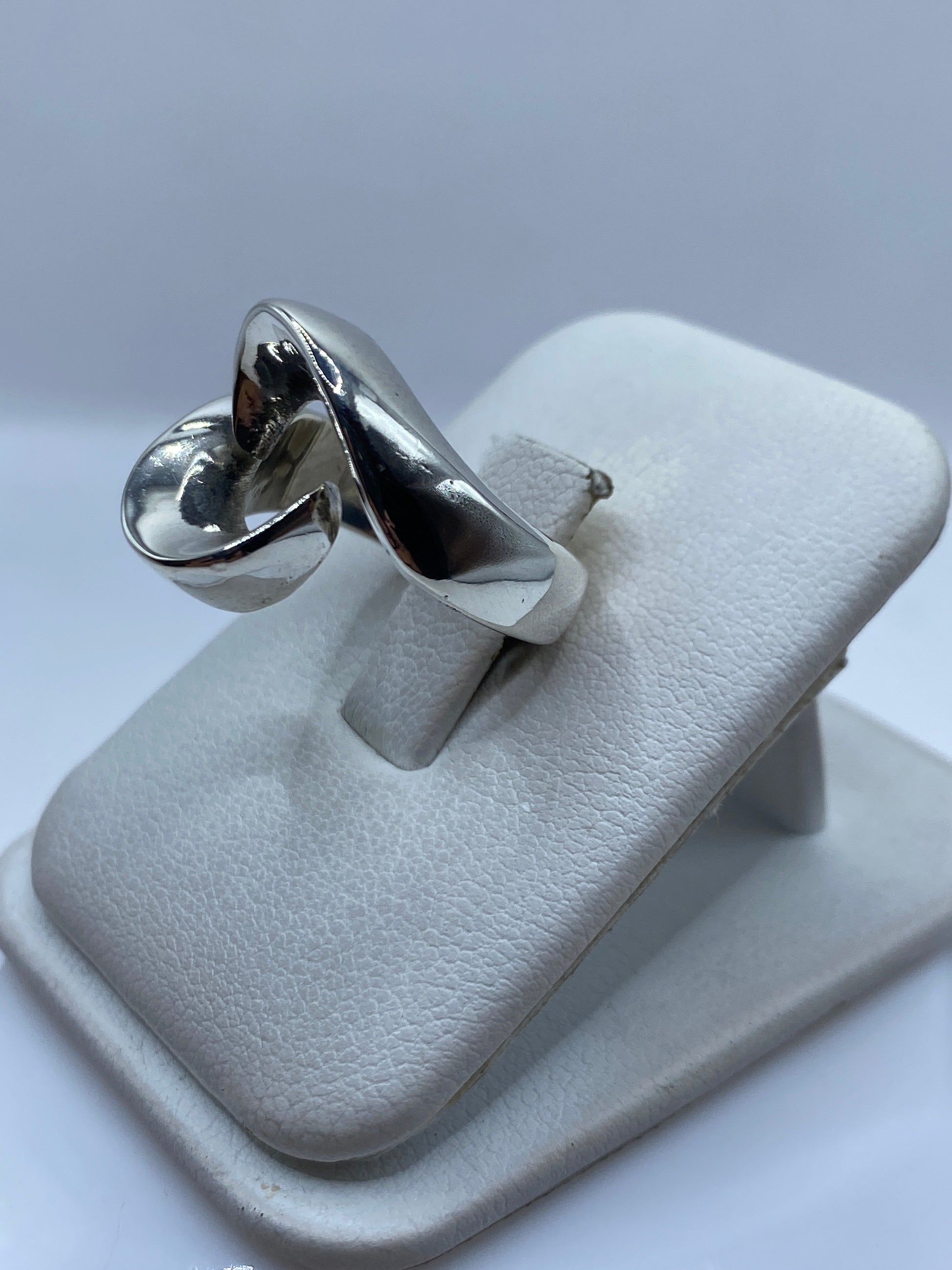 Anillo de plata moderno en dedo, mostrando el juego de volúmenes y luz