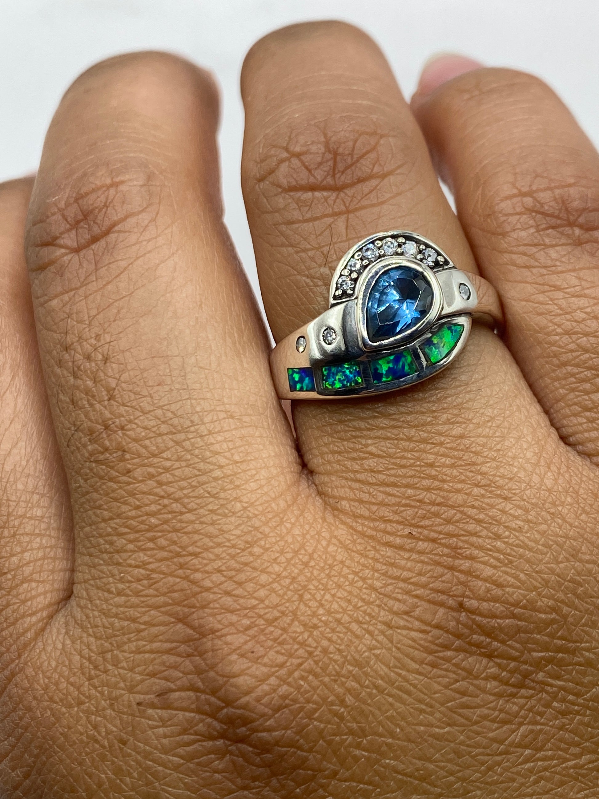 Anillo de plata con ópalo de fuego puesto en dedo, vista frontal del diseño combinado