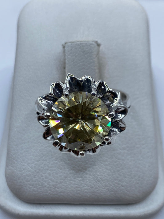 Anillo de plata .925 con circonia amarillo verdoso engastada en corona floral, visto de frente en estuche blanco