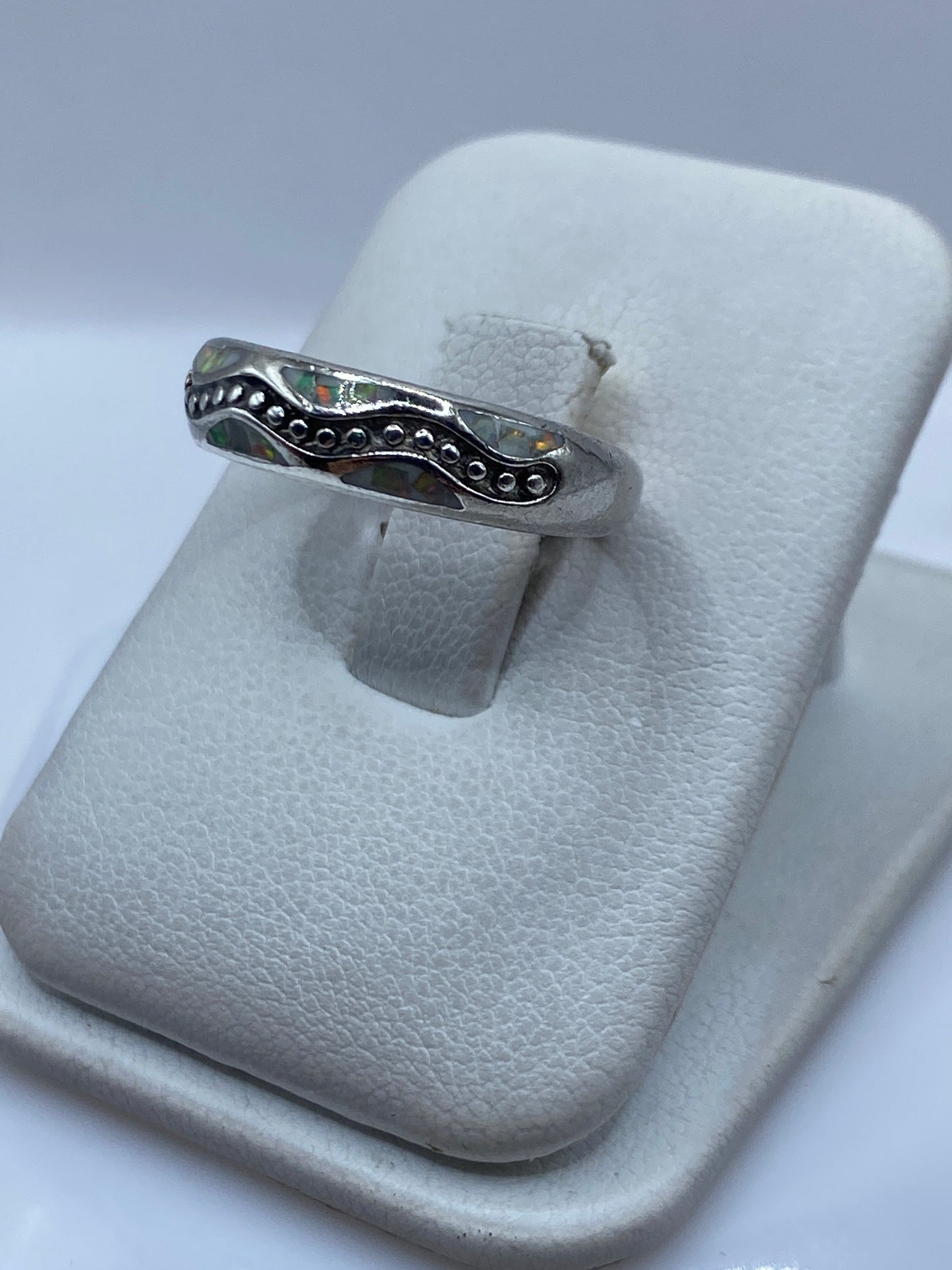 Anillo en la mano mostrando los tonos multicolores del ópalo de fuego — naranjas, verdes y azules