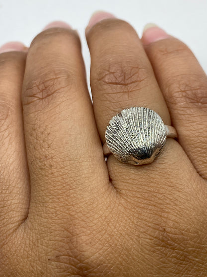 Anillo de concha marina en la mano, mostrando el acabado pulido