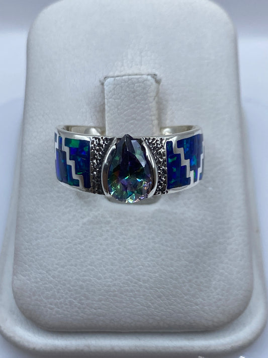 Anillo de plata .950 con ópalo de fuego azul en posición frontal sobre las manos