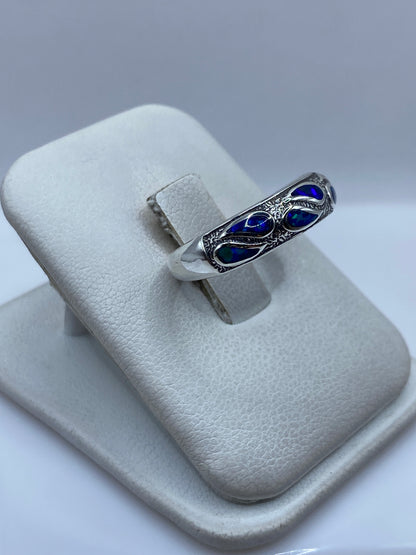 Detalle frontal del anillo mostrando el ópalo azul con juego de luces en la mano